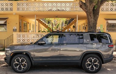 Miami, Florida, ABD - 01 Nisan 2025: elektrikli araba Rivian R1S SUV tipi. Dışarıda park edilmiş elektrikli Rivian R1S 'ler var. Gri elektrikli araba, yan görüş. 2023 Rivian R1S Fırlatma Sürüm Elektrikli off-road SUV araba.