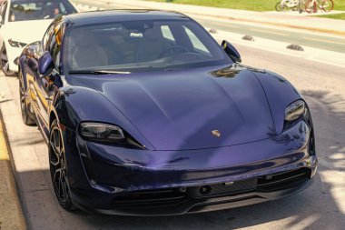 Miami, Florida, ABD - 4 Nisan 2025: Lüks elektrikli araba Porsche Taycan. Porsche Taycan dışarıda park etmiş. Mavi elektrikli araba, ön manzara. Porsche Taycan 2020 elektrikli araba.