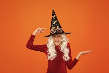 Cadılar Bayramı 'nda cadı şapkası giymiş bir kız. Mutlu Cadılar Bayramı. Cadılar Bayramı kostümlü cadı kız portakalı izole etti. Cadılar Bayramı kostüm partisi kutlaması. Tüm Cadılar Bayramı cadıları. Yarasa şapkası. Reklam..