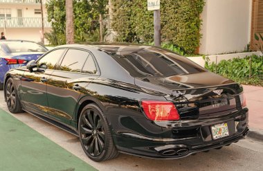 Miami, Florida, ABD - 17 Nisan 2025: 2022 Bentley Flying Spur W12 sedan araba. Lüks araba Bentley Uçan Mahmuz W12. Araba Bentley Uçan Mahmuz W12 dışarıda park halinde. Siyah araba, yan köşe manzaralı..