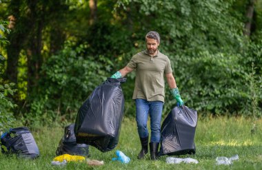 Toprak kirliliği, çevresel sorunlar. Plastik çöp yığını. Doğanın kirliliği. Park temizliği. Çevre kirliliği. Çöpleri toplayan gönüllü. İnsan doğada atık topluyor..