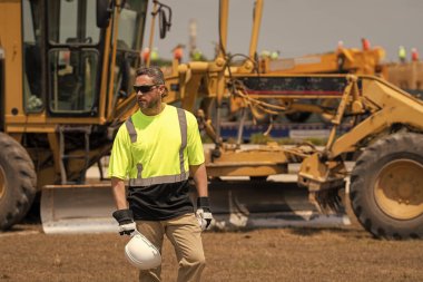 Şantiyedeki adam. İnşaat mühendisliği. İnşaat alanında mühendis var. Denetmen işçi üniforma giyer. İşteki en üst düzey yönetici. İşçi bayramı. Binanın dış tarafında. Güvenliğin sağlanması.