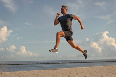 Spor yaşam tarzı. Yazın koşan sporcu. Spor koşuculuğu eğitimi. Sağlıklı yaşam tarzı ve günlük koşular. Koşan koşucu. Spor ve spor. Kumsalda koşan adam. Enerjik koşucu.