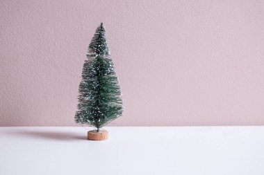 Pembe arka planı olan küçük bir Noel ağacına yaklaş.