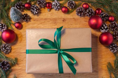 Üzerinde yeşil kurdele ve süsler olan kahverengi noel hediyesini kapat..