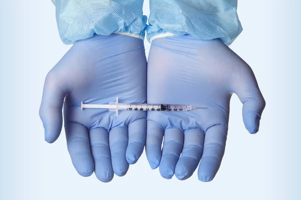 Jeringa con una vacuna en las manos con guantes azules de látex —  Fotos de Stock
