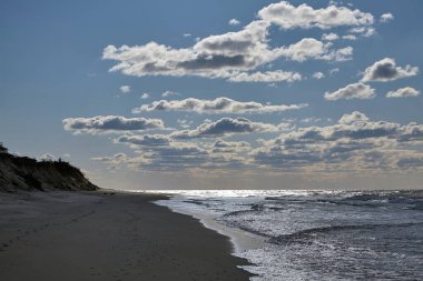 Kumlu deniz plajı, güzel bulutlar ve gölgelerle.