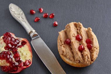 Ekmeğe yayılmış, nar tohumlarıyla süslenmiş ev yapımı ezmeli sandviç.
