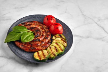 Tabakta sebze ve otlarla ızgara sosis.