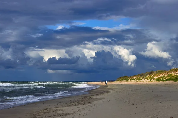 Blå, dramatiske skyer og solstråler bryter gjennom over stranden – stockfoto