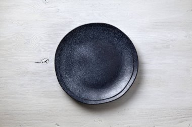 Dark ceramic plate on a white wooden background