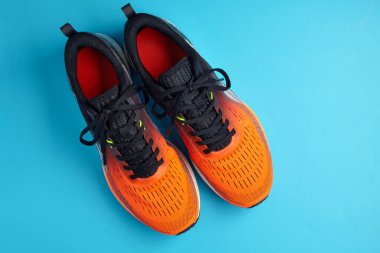 Mavi arka planda turuncu spor ayakkabıları olan bir stüdyo resmi