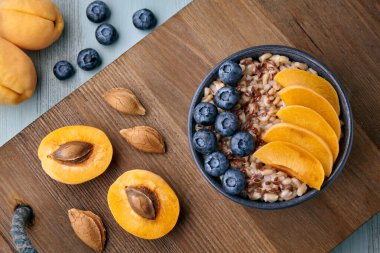 Tahta tepside keten tohumu, yabanmersini ve kayısı dilimli tam tahıllı yulaf ezmesi. Enerji kahvaltısı