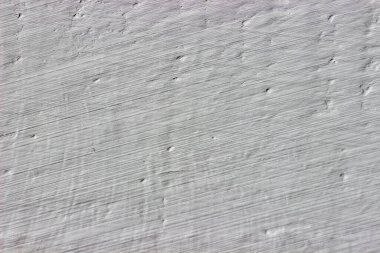 Gri boyayla boyanmış kabaca alçılı bir duvar.