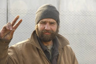 Kirli giysiler içinde sakallı genç evsiz adam Moldova. Cahul. 27.01.2020.