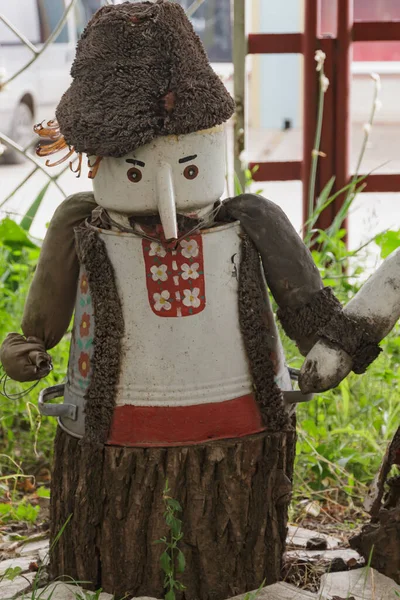 Moldova 'nın ağaç kütüğündeki Moldova kostümüyle kovadan ve çaydanlıktan yapılmış bir adam. Cahul. 8.06.2019..
