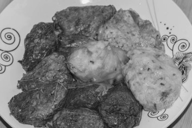  Lahana dolması ve üzüm yaprağı lahanası siyah beyaz bir tabakta yuvarlanıyor.