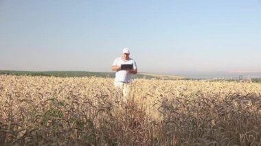 Üzerinde Sovyet kırmızı yıldızı olan beyaz şapkalı bir adam elinde dizüstü bilgisayarla bir yaz tarlasında çavdar ekmeğiyle yürüyor..