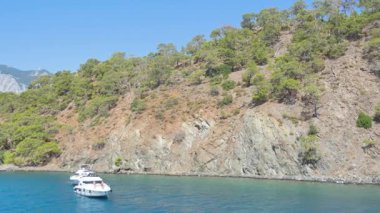 Türk Rivierası 'nın güzelliğini yansıtan huzurlu bir yaz sahnesi. Video, beyaz teknelerin demirlediği güzel bir körfez boyunca ilerliyor..