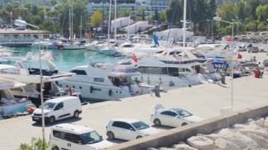 Yüksek açılı görüntüler, yatlarla dolu hareketli, modern bir marina ile Akdeniz sahilinin huzurlu, doğal güzelliği arasındaki farkı yakalıyor..