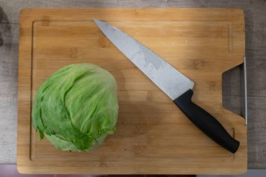 Ahşap tabakta kirli bıçak ve marul..