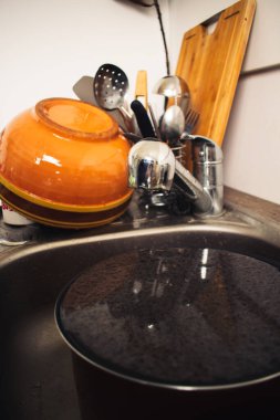 Bulaşıkları kirli bir tencereyle yıkadı.