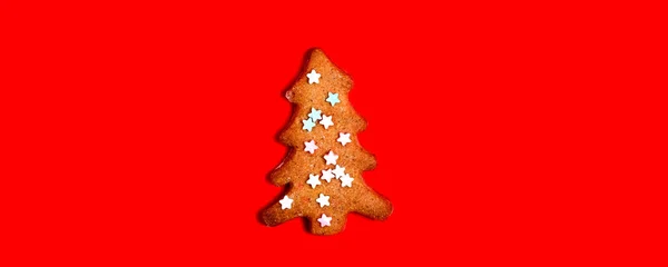 Gingerbread christmas tree cookie decorated with mastic star icing on bright red background. Festive, holiday cooking concept