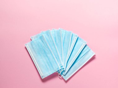 Pastel pembe arka planda tıbbi koruyucu maskeler. Bireysel, tek kullanımlık cerrahi maske düz desen. Karantina sağlık hizmetleri, hijyen ve koronavirüs koruma kavramı.