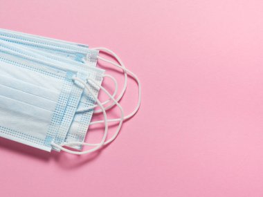 Pastel pembe arka planda tıbbi koruyucu maskeler. Bireysel, tek kullanımlık cerrahi maske düz desen. Karantina sağlık hizmetleri, hijyen ve koronavirüs koruma kavramı.