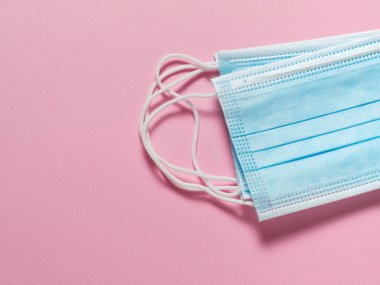 Pastel pembe arka planda tıbbi koruyucu maskeler. Bireysel, tek kullanımlık cerrahi maske düz desen. Karantina sağlık hizmetleri, hijyen ve koronavirüs koruma kavramı.