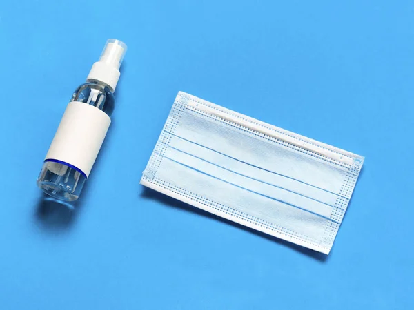 Medical protective mask, and hand sanitizer on a blue background. Individual, disposable hygiene equipment. Quarantine healthcare, hygiene and coronavirus protection concept