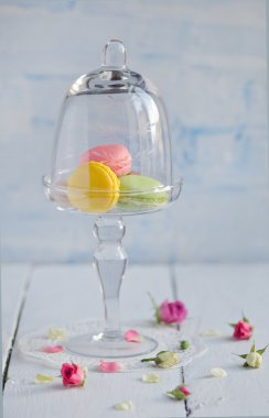 Beyaz ahşap masa üzerinde bir cam tepsi içinde renkli macaroons yakından görmek