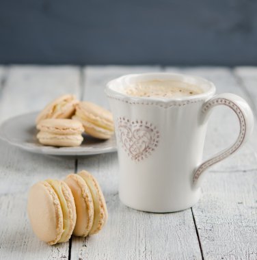 ahşap bir masa üzerinde bir fincan cappuccino ile vanilya macaroons yakından görmek