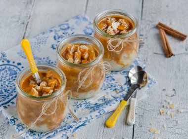 Ahşap masa üzerinde cam kavanozlara karamelize elmalı tatlı lezzetli süt-pirinç 