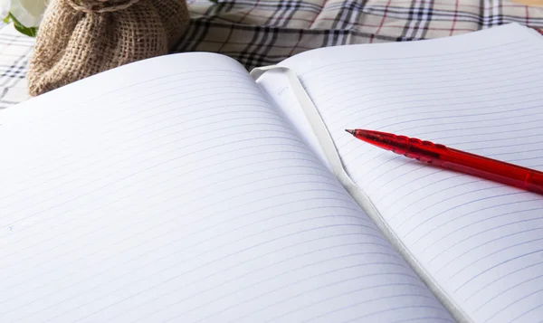 a pen and blank paper of open book on the table