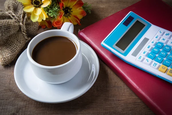 Cup of coffee, books and calculator, on table wood