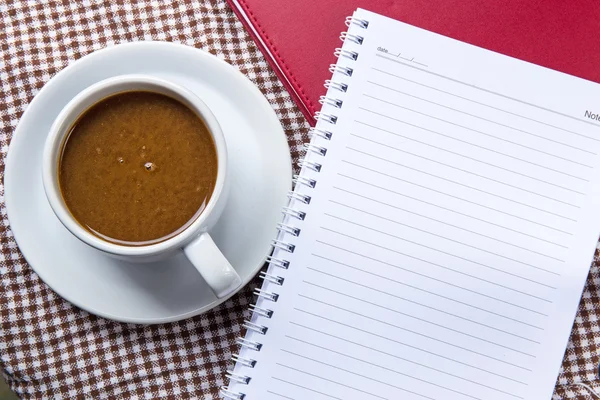 Xícara de café e bloco de notas em mesa de madeira — Fotografia de Stock