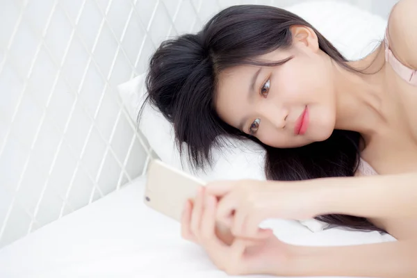 美しい若いですアジアの女性セクシーで下着でチャット上の携帯電話でベッドルーム 幸せな女の子でランジェリー見ますソーシャルメディアスマートフォン上に横たわる コミュニケーションとライフスタイルの概念 — ストック写真