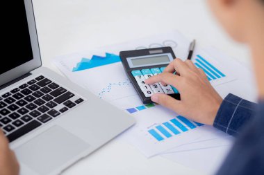 Muhasebecilik için hesap makinesi kullanan genç Asyalı iş adamının eli, finans ve rapor grafiği, istatistik, yatırım ve gelir kârı, grafikle analiz eden iş adamı.