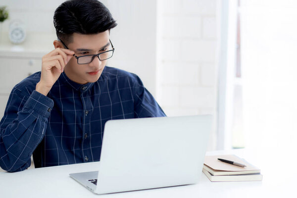 Young business man in glasses working from home with laptop computer on desk, freelance male sitting stay home using notebook for communication on table, entrepreneur in startup business, new normal.