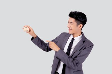 Genç Asyalı iş adamı, gelecek için tasarruf, sigorta acentesi ve kredi, mülkiyet evi, borç ve finans kredisi, satın alma ve yeniden finanse etme, emlak yatırımının ev sembolünü elinde tutuyor..