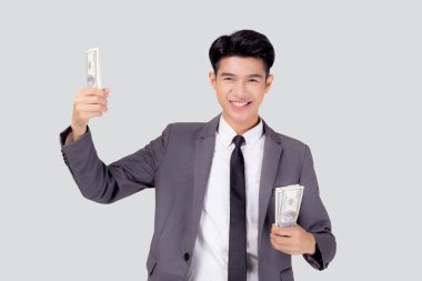 Asyalı genç iş adamı parayı beyaz arka planda tutuyor, takım elbiseli işadamı banknot ve başarı tutuyor ve finans, tasarruf ve yatırım, gelir ve harcamalarla heyecanlanıyor.