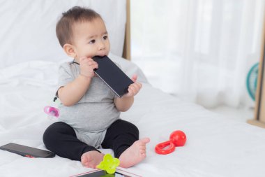 Küçük şirin bir kızın portresi yatak odasında rahat bir şekilde oturuyor, bebek mutluluğu, 6-11 aylık bebek masumiyeti ve ifadesiyle neşeli, çocuk büyüsü, kapalı mekanda, bir kişi.