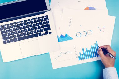 İş adamı görünümlü belgelerin eli, masadaki grafik, grafik ve dizüstü bilgisayarla istatistiksel finans, finans ve yatırım, dijital pazarlama, iş ve iletişim kavramını rapor etmektedir..