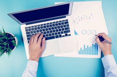 İş adamı görünümlü belgelerin eli, masadaki grafik, grafik ve dizüstü bilgisayarla istatistiksel finans, finans ve yatırım, dijital pazarlama, iş ve iletişim kavramını rapor etmektedir..