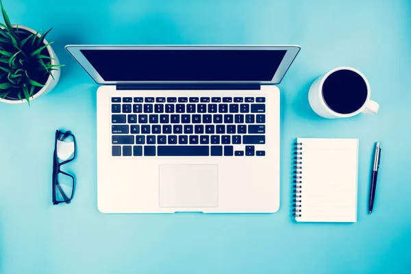 Flat lay of laptop computer and plant and cup of coffee on desk in office, workplace and notebook and glasses and potted tree and book, workspace and copy space, top view, business concept.