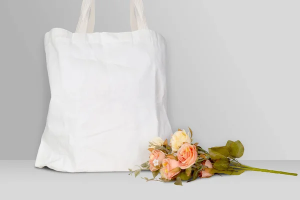 Mockup white tote bag fabric for shopping and flower on desk, mock up canvas bag textile with reusable.