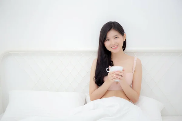 若いですアジアのセクシーな女性で下着のコーヒーを飲みます午前中にベッドの上でベッドで アジアの女の子とともに魅惑的なフィット飲料用リラックスした後目を覚ます ライフスタイルの概念 — ストック写真