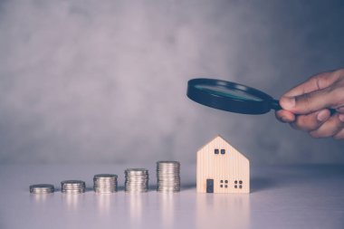 Ellerinde büyüteç ev modeli bulunan işadamlarının elleri, kar amaçlı gayrimenkul ve mülk yatırımları, konut ve gelir planlaması, kredi ve ipotek, iş konsepti.