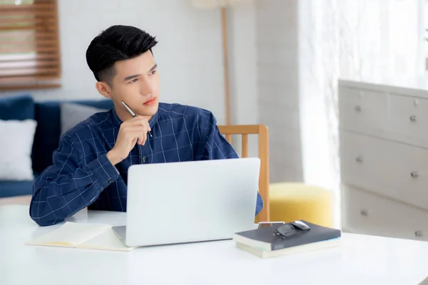 家の机の上でノートパソコンを使って仕事をしている若いアジアのビジネスマン 男性の研究と学習 ビジネスマンの考え方 ビジネスとコミュニケーションの概念についてのメモ — ストック写真